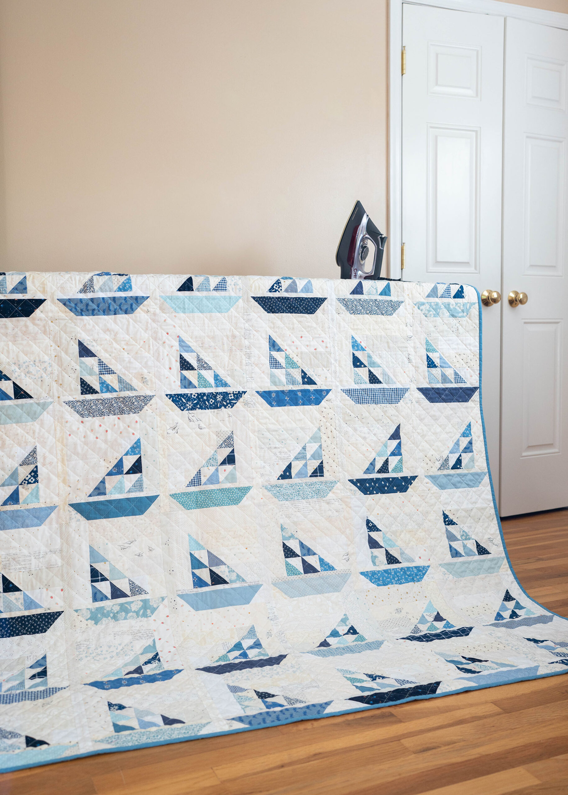 A patchwork quilt in a variation of blues and neutrals forming little sailboats.