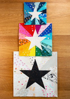 Three sizes of the Scrap Burst Star quilt block in a blue colorway, a rainbow colorway, and finally a low volume colorway.